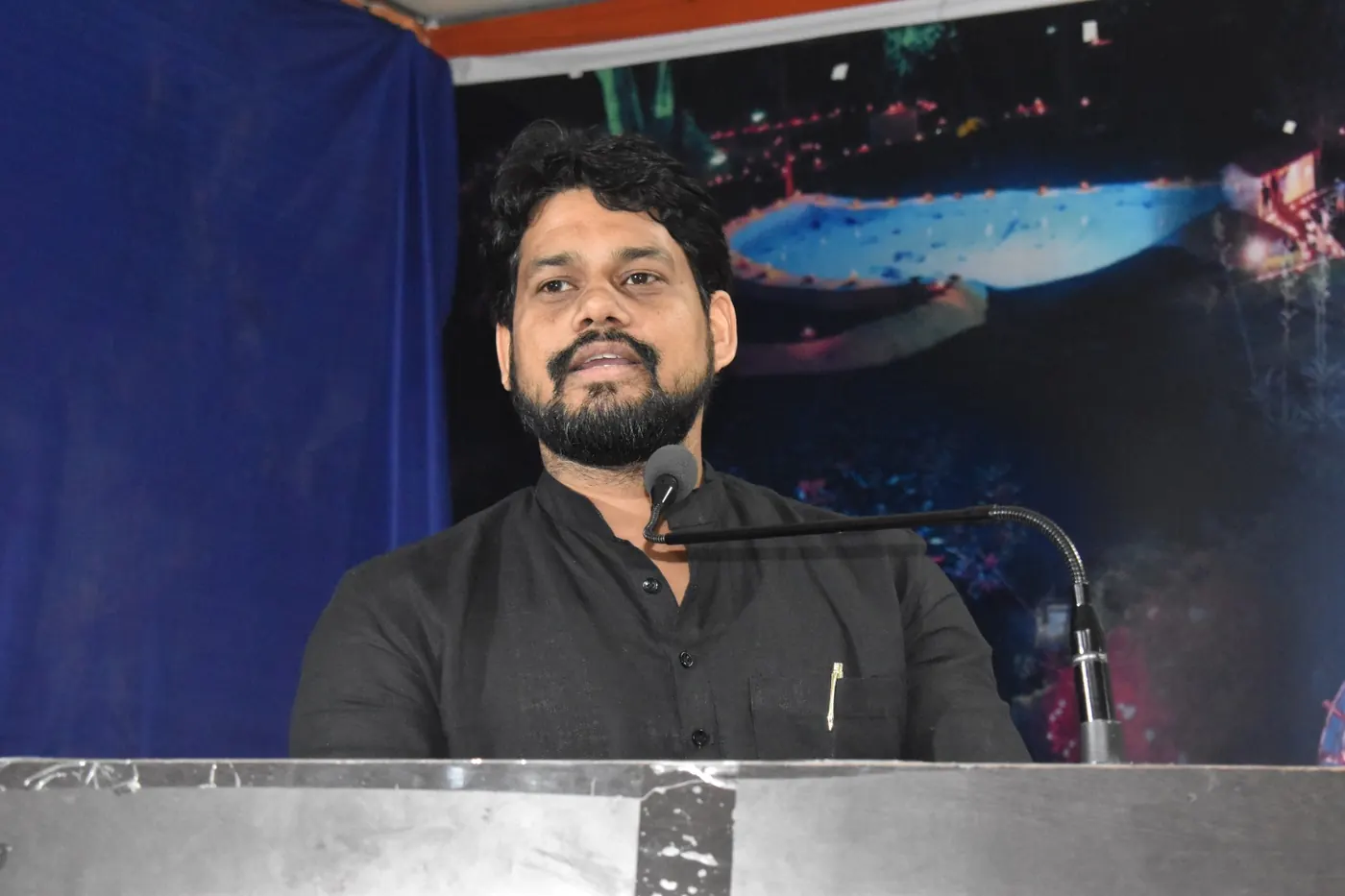 Dr. Harish Pandey speaking at a podium microphone