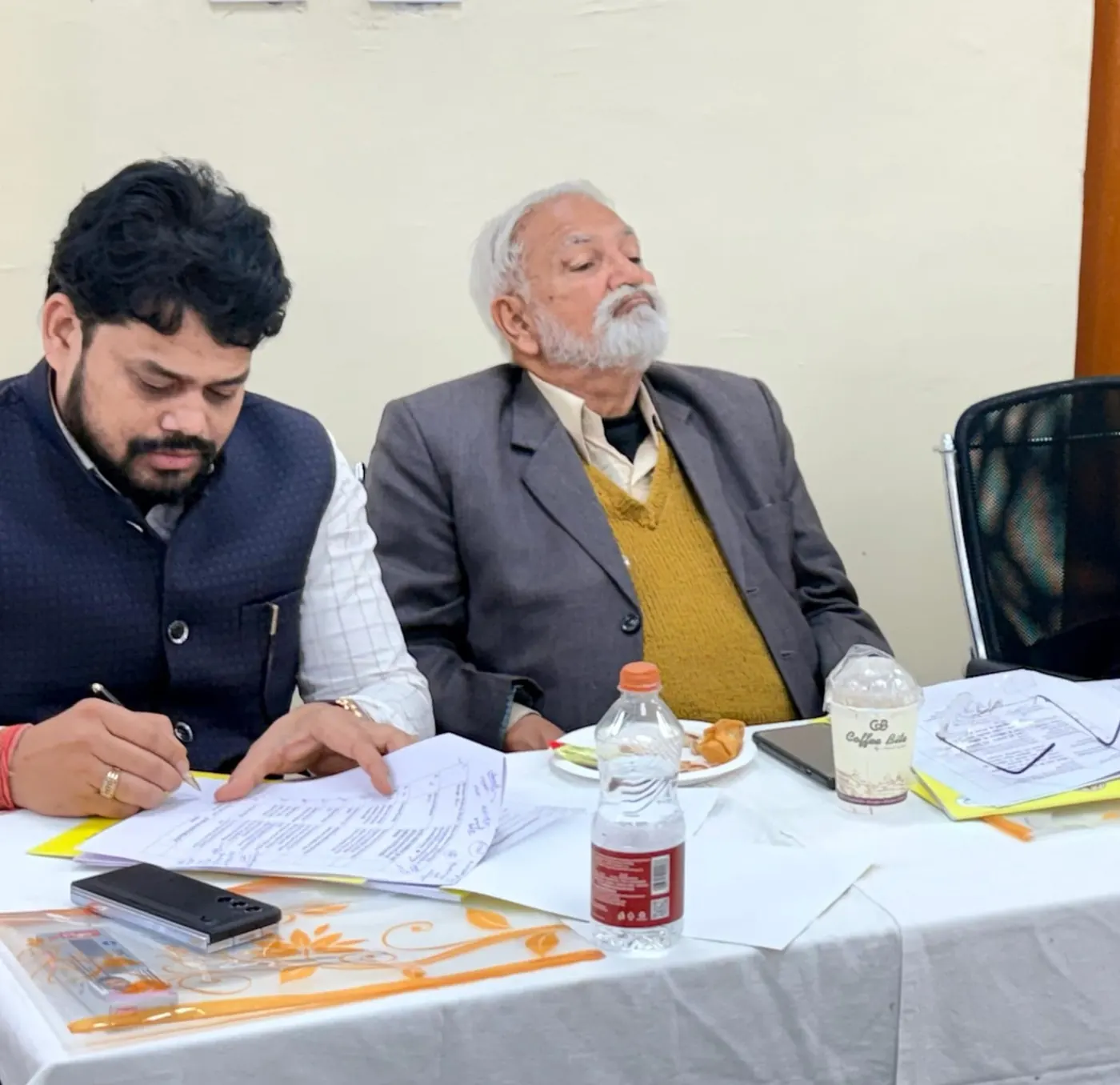 Dr. Harish Pandey reviewing documents at a panel table
